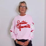 Person wearing a pink sweatshirt with 'Santa's favorite' text against a plain background