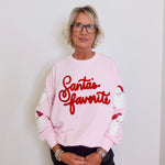 Person wearing a pink sweatshirt with 'Santa's favorite' text against a white background