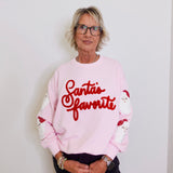 Person wearing a pink sweatshirt with 'Santa's favorite' text against a white background