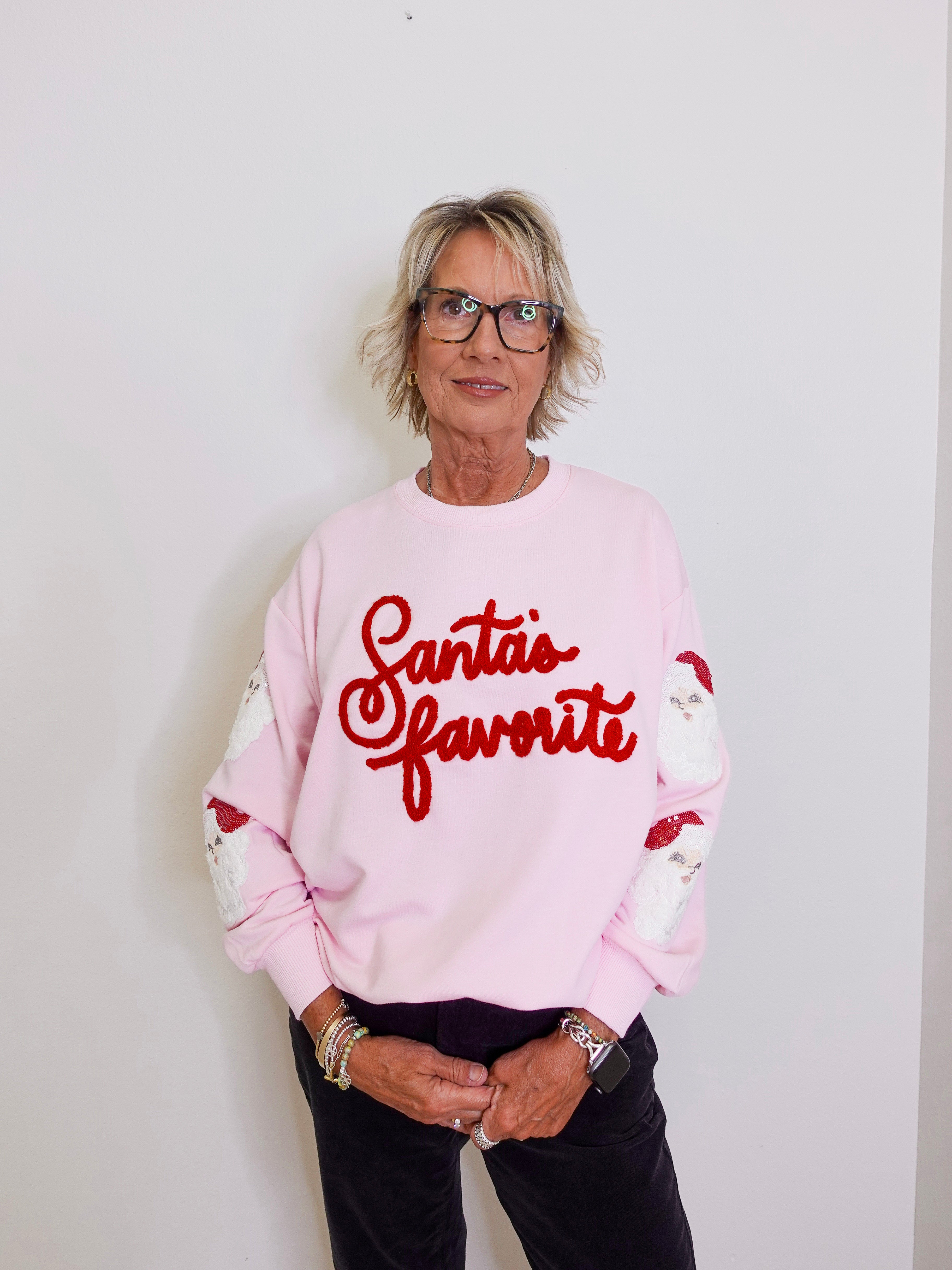 Person wearing a pink sweatshirt with 'Santa's favorite' text against a white background