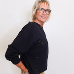 woman wearing a black sweatshirt with black sequins on it