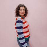 Woman wearing a colorful striped sweater against a pink background