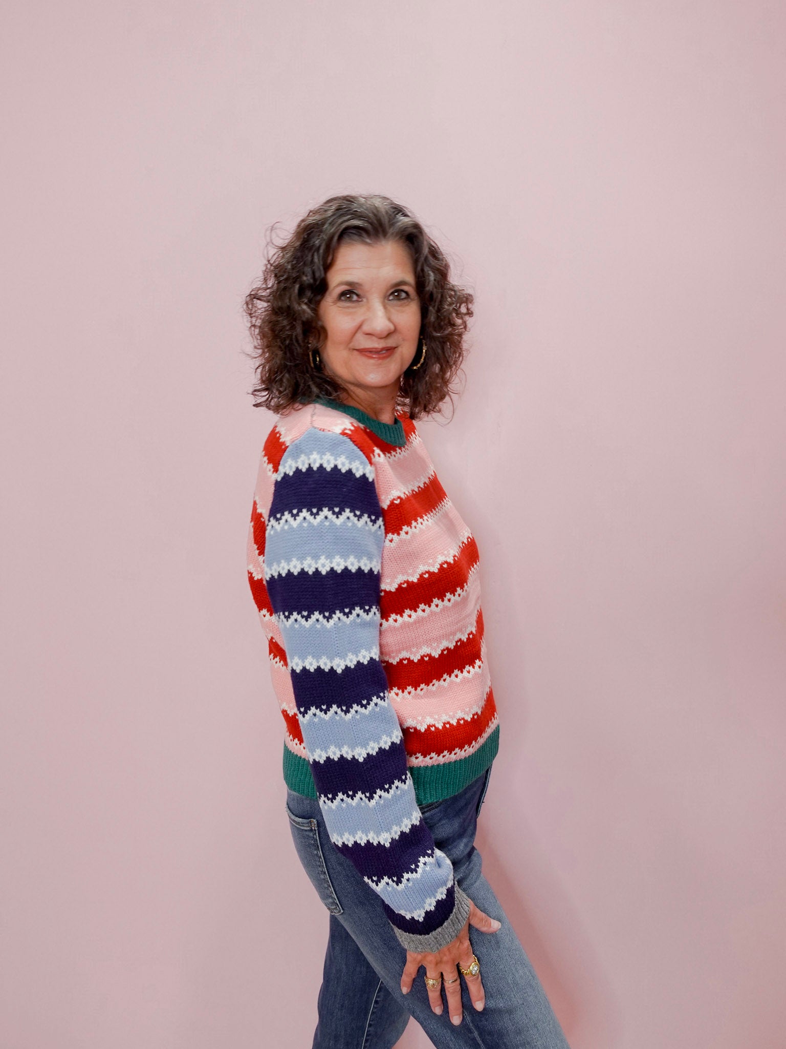 Woman wearing a colorful striped sweater against a pink background