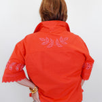 Person wearing an orange embroidered jacket on a white background