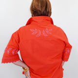 Person wearing an orange embroidered jacket on a white background