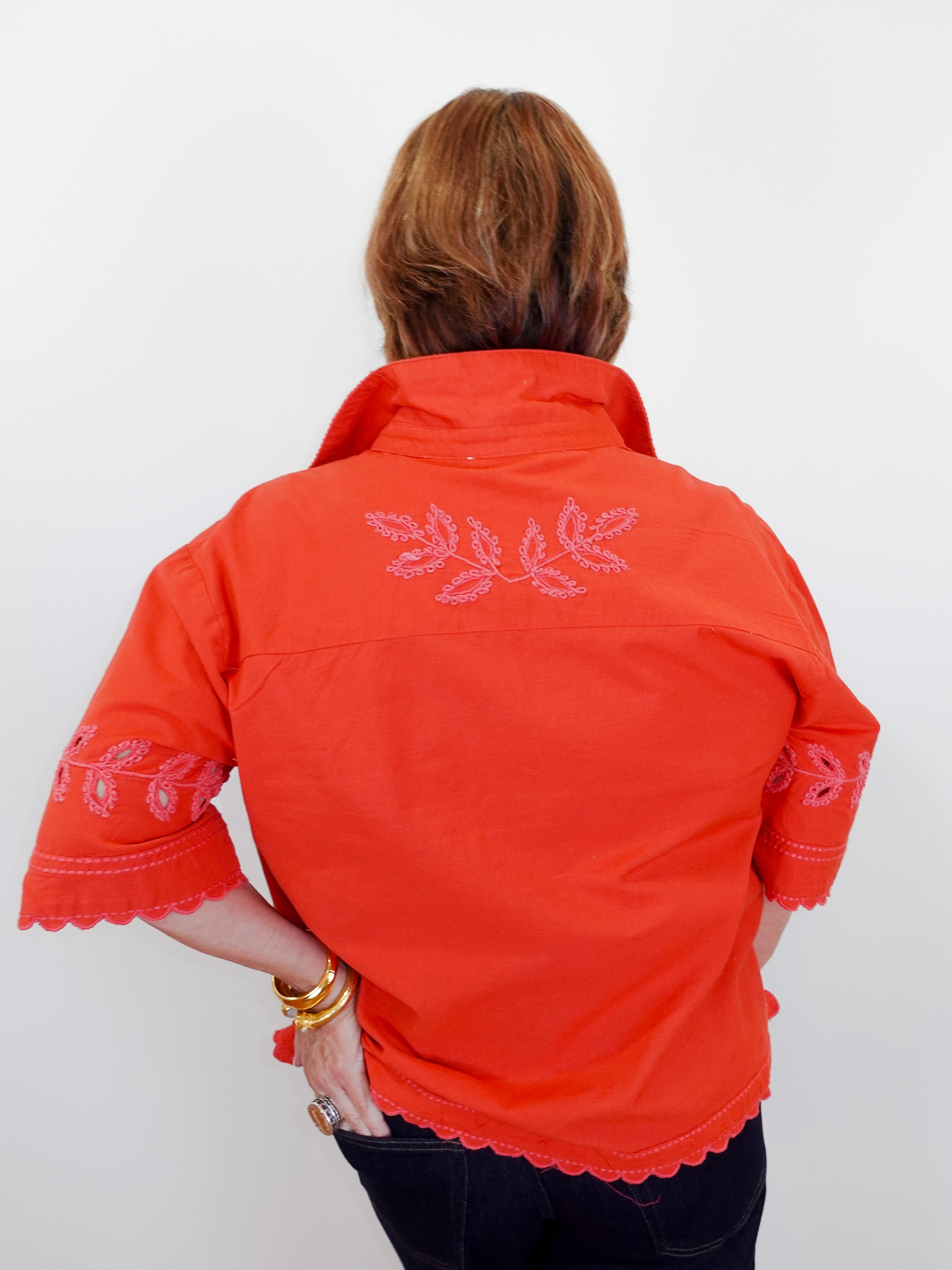 Person wearing an orange embroidered jacket on a white background