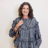 Woman wearing a patterned blouse with a plain background