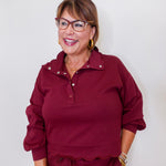 Woman wearing a burgundy outfit with glasses against a white background