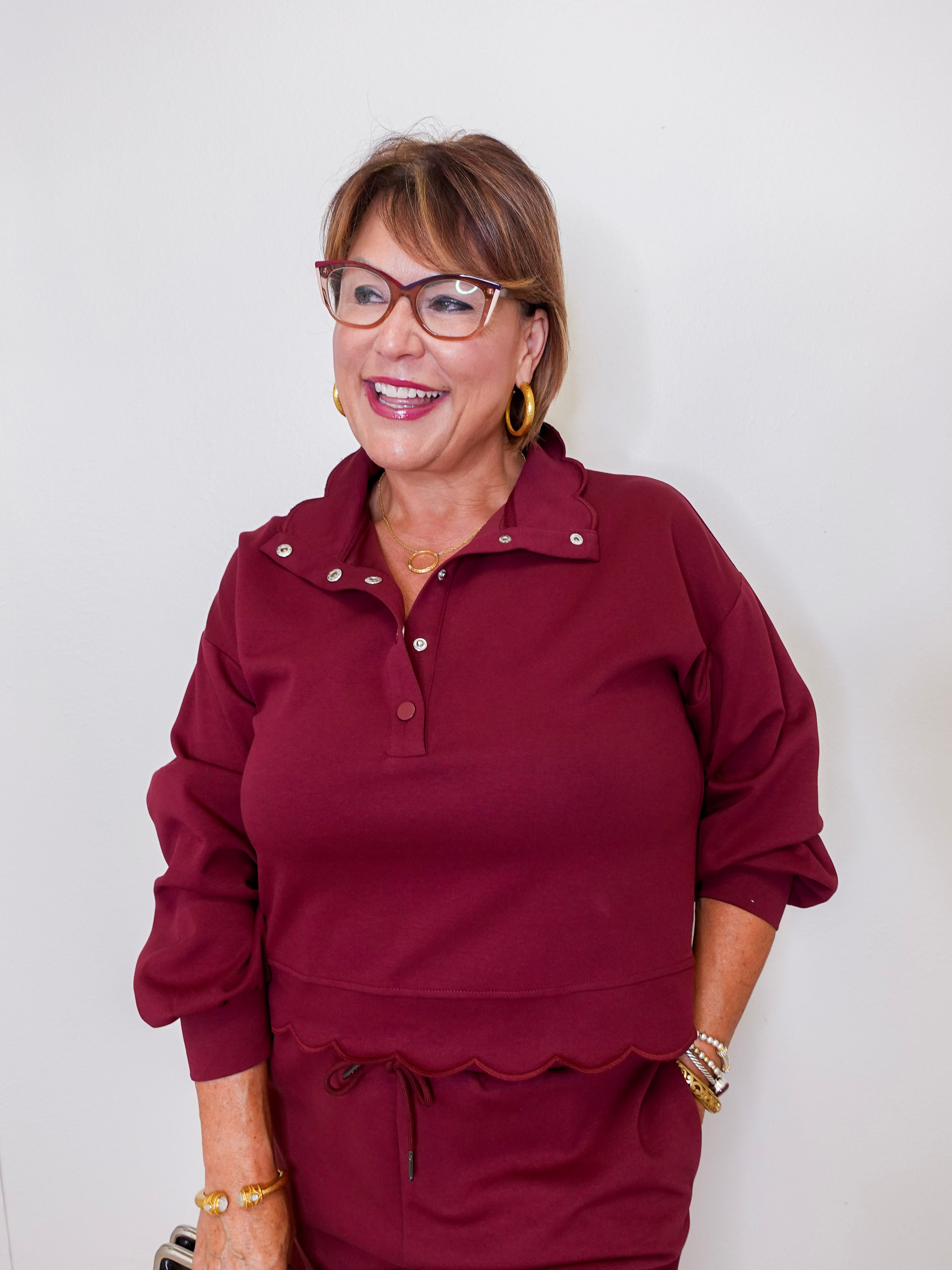 Woman wearing a burgundy outfit with glasses against a white background