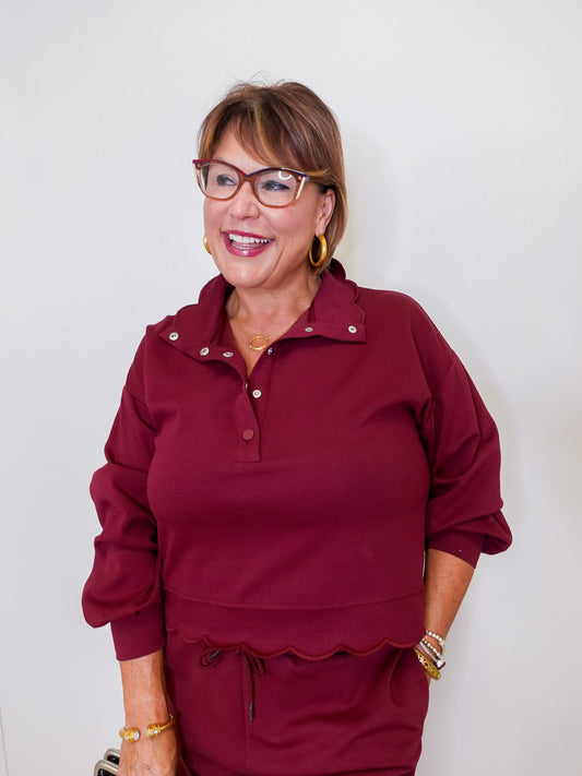 Woman wearing a burgundy outfit with glasses against a white background