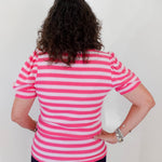 Person wearing a pink and white striped shirt against a plain background