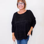 Woman wearing a black sweater and blue jeans against a white background