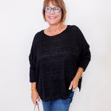 Woman wearing a black sweater and blue jeans against a white background