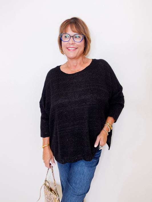 Woman wearing a black sweater and blue jeans against a white background