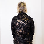 Person wearing a black floral-patterned jacket against a white background