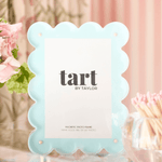 Light blue scalloped photo frame with 'tart by Taylor' branding on a blurred background.