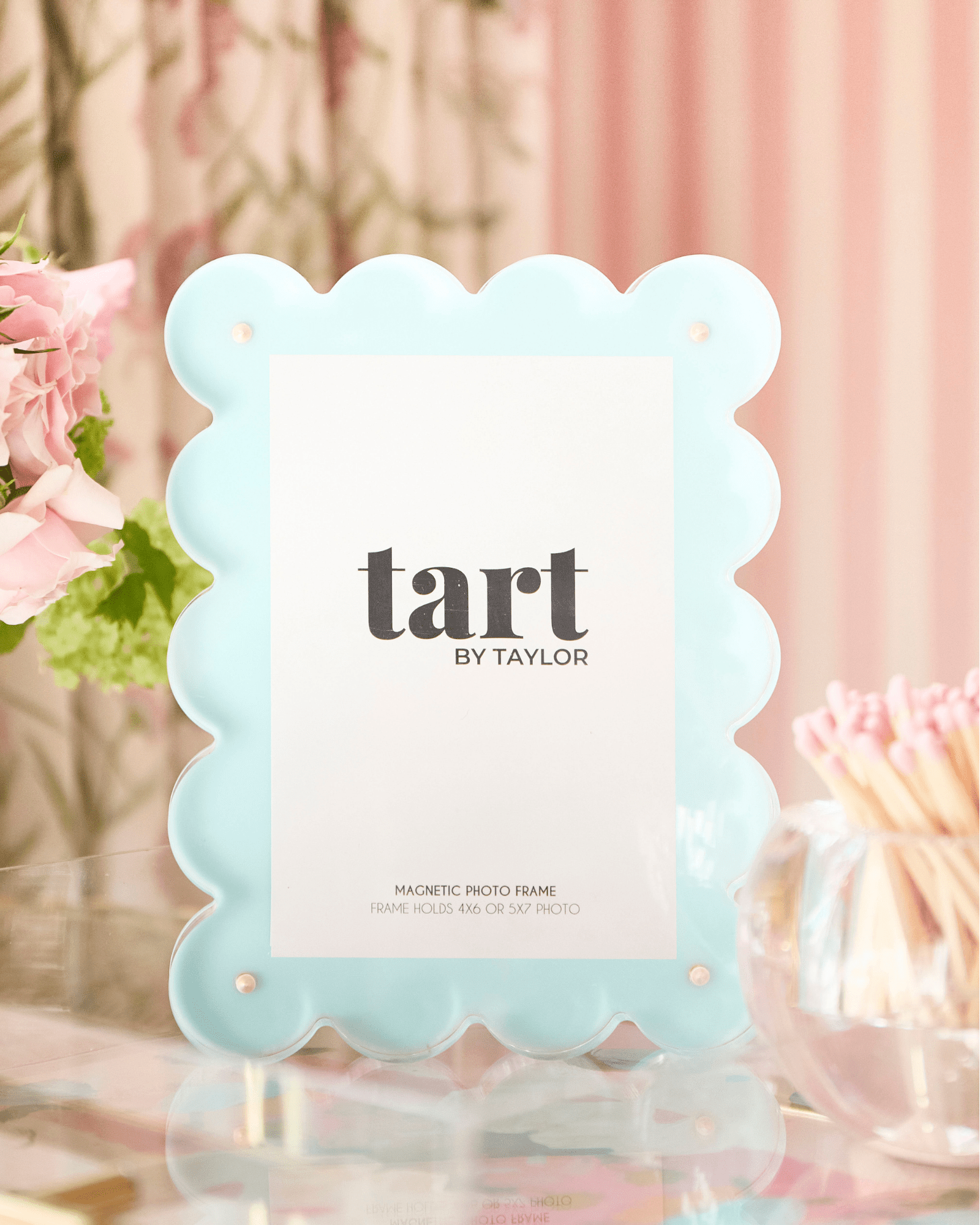 Light blue scalloped photo frame with 'tart by Taylor' branding on a blurred background.