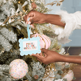 Person decorating a Christmas tree with a 'photo frame ornament' tag.