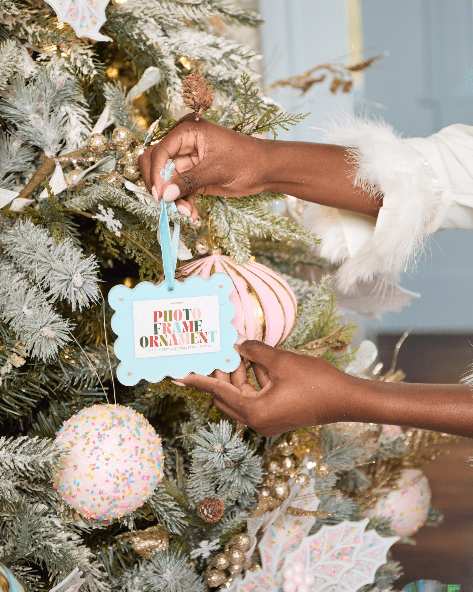 Person decorating a Christmas tree with a 'photo frame ornament' tag.