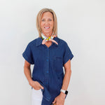 Woman wearing a blue shirt and white pants with a neutral background