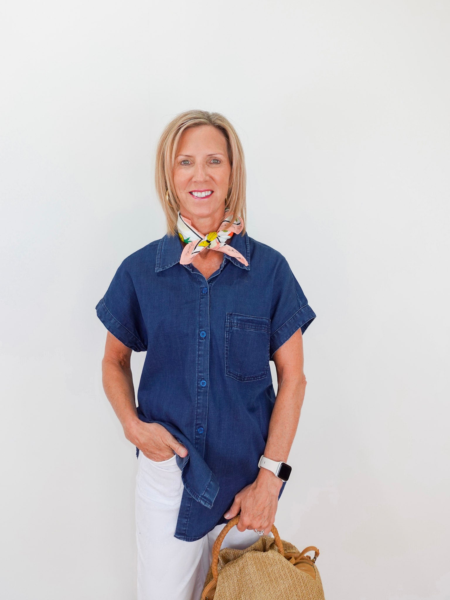 Woman wearing a blue shirt and white pants with a neutral background