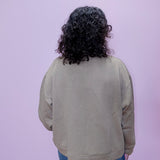 Person wearing a beige sweater with a textured pattern on a light purple background