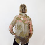 Person wearing a floral patterned shirt against a white wall