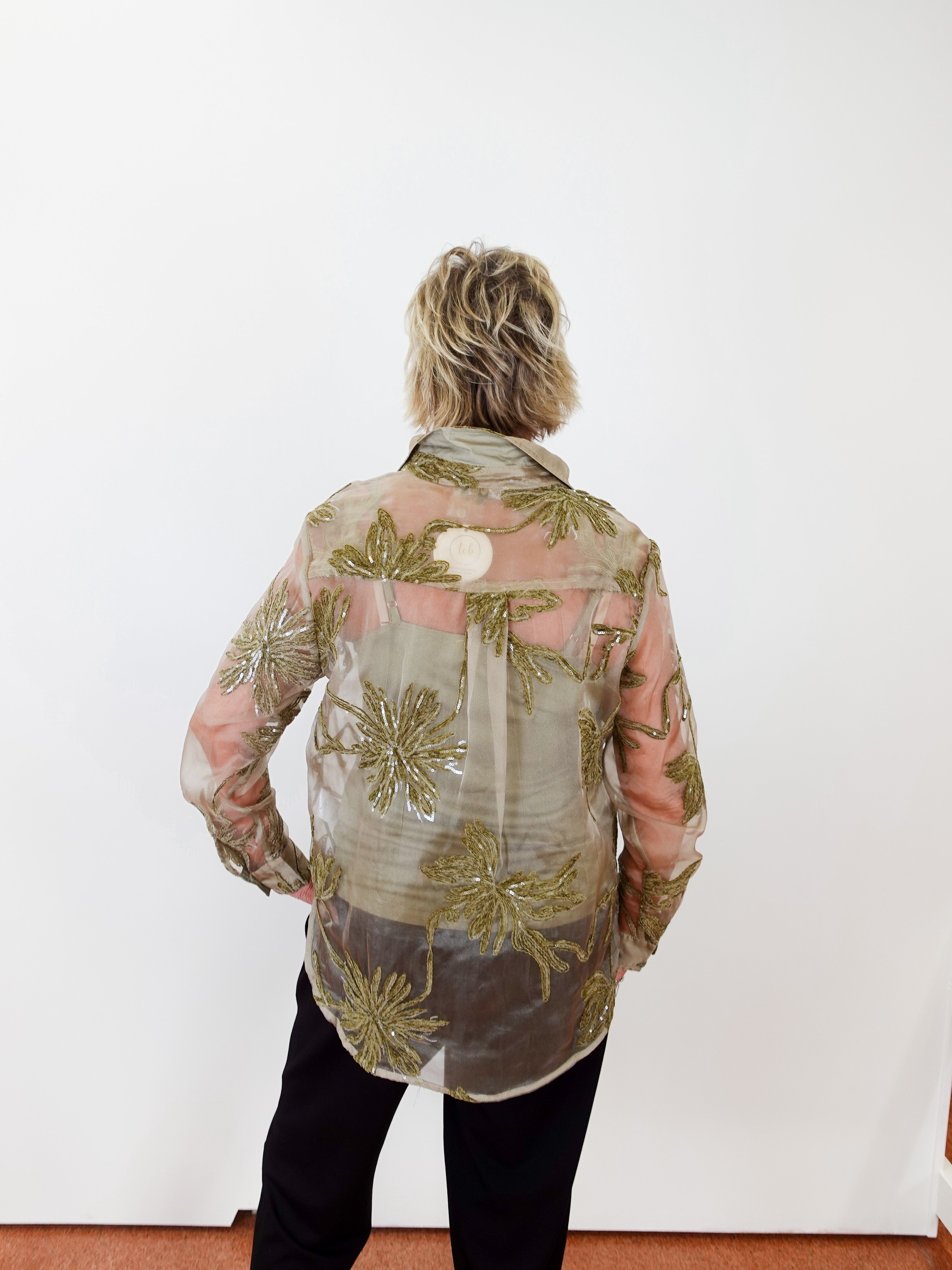 Person wearing a floral patterned shirt against a white wall