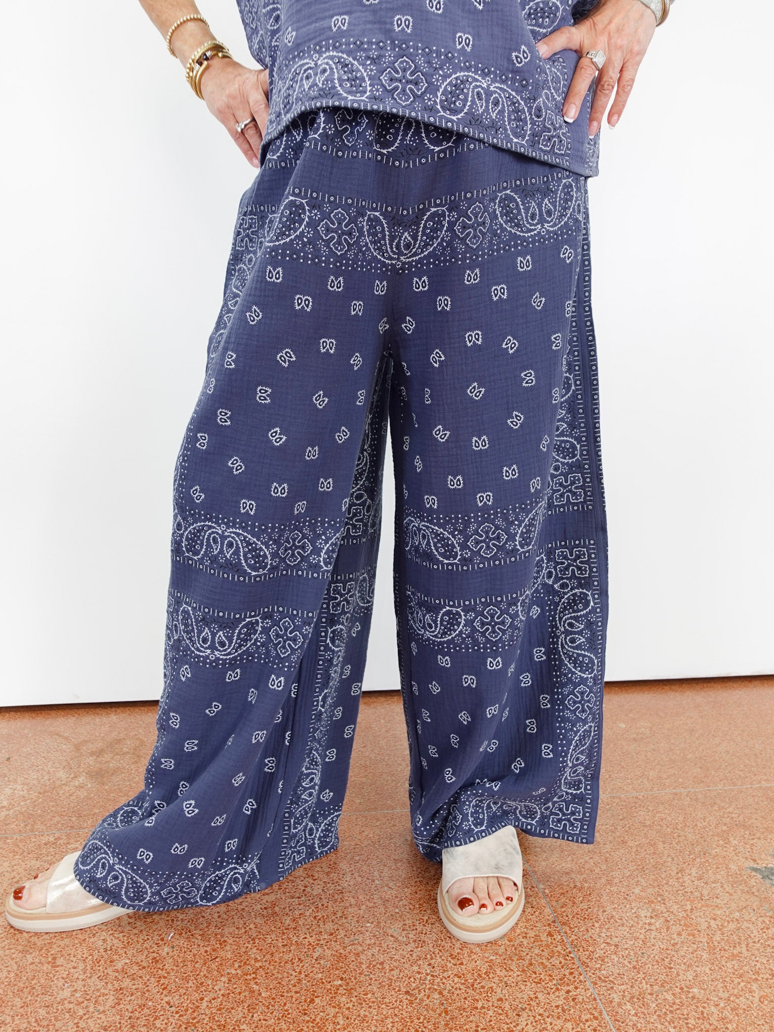 Person wearing blue paisley pants on a plain background