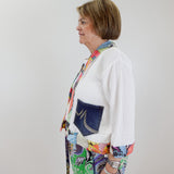 Person wearing a colorful outfit with a white shirt and patterned pants against a plain background