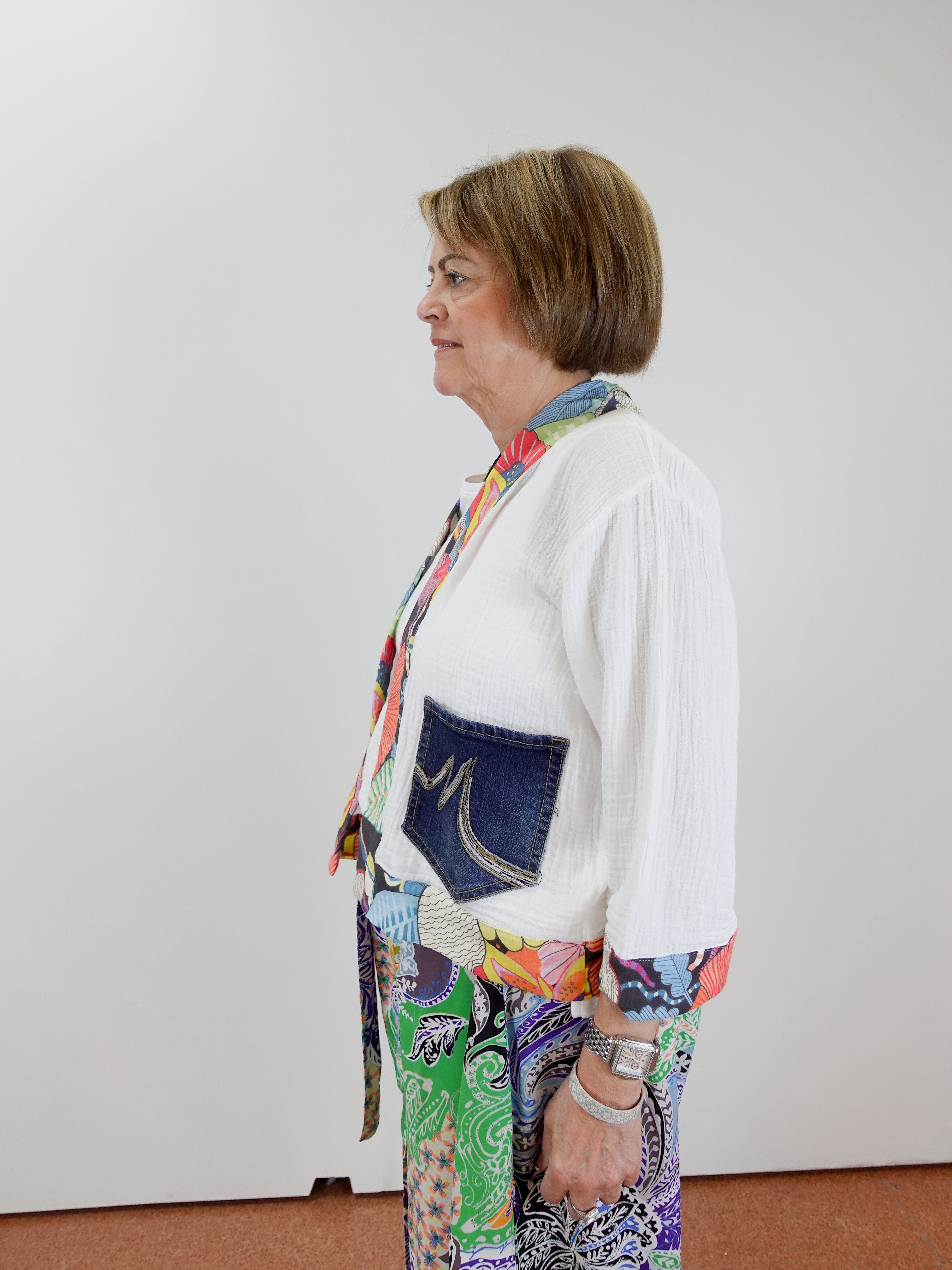 Person wearing a colorful outfit with a white shirt and patterned pants against a plain background