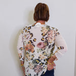 Person wearing a floral and leopard print top against a white wall