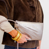 Person holding a silver clutch with a plain background