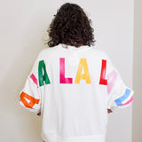 Person wearing a white sweatshirt with colorful letters on the back against a plain background