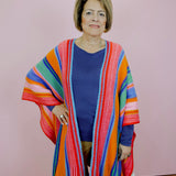 Woman wearing a colorful striped cardigan against a pink background