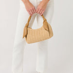 Person holding a woven handbag with a plain background