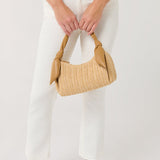 Person holding a woven handbag with a plain background
