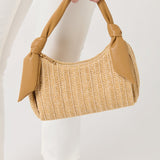 Beige woven handbag with leather handles held by a person on a white background