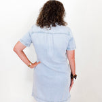 Person wearing a light blue denim dress against a white background