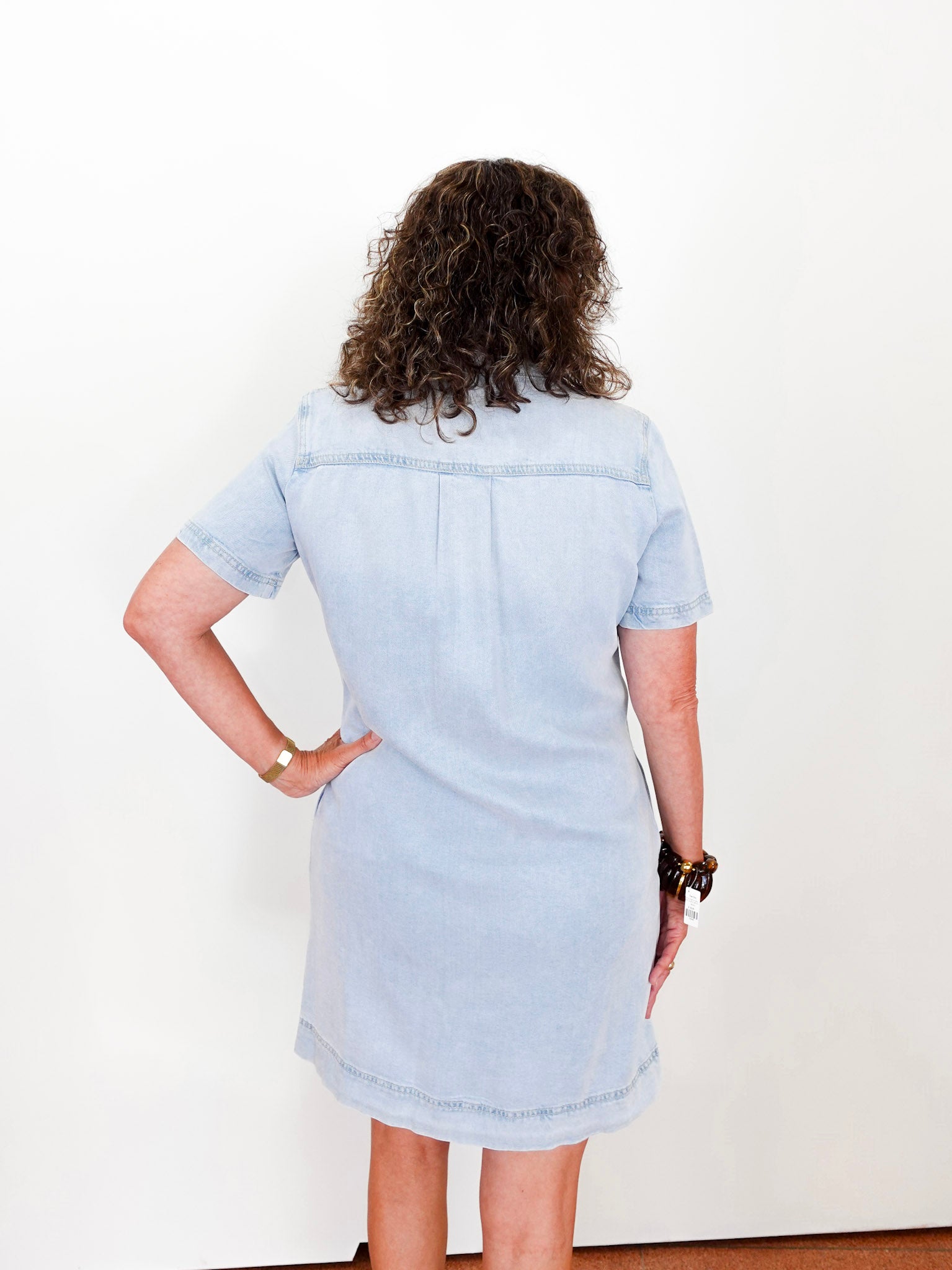 Person wearing a light blue denim dress against a white background