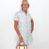 Woman wearing a floral dress holding a handbag against a white background