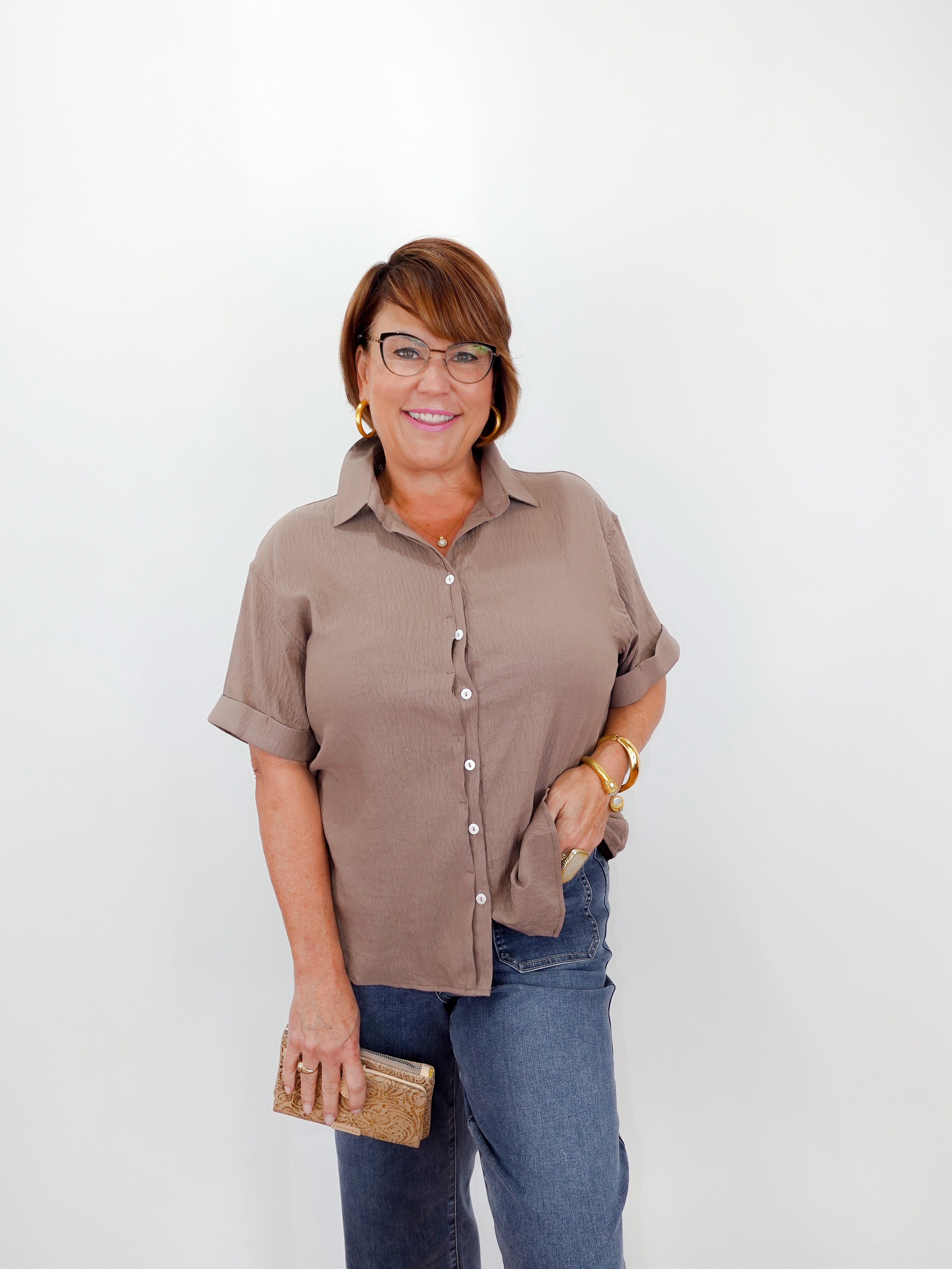 Woman wearing a brown shirt and blue jeans against a white background