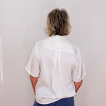 Person wearing a white shirt and blue jeans against a plain background