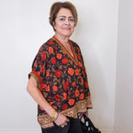 a women wearing a black short sleeve floral print top with black pants, on a white background 