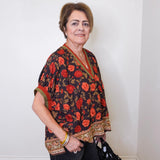 a women wearing a black short sleeve floral print top with black pants, on a white background 
