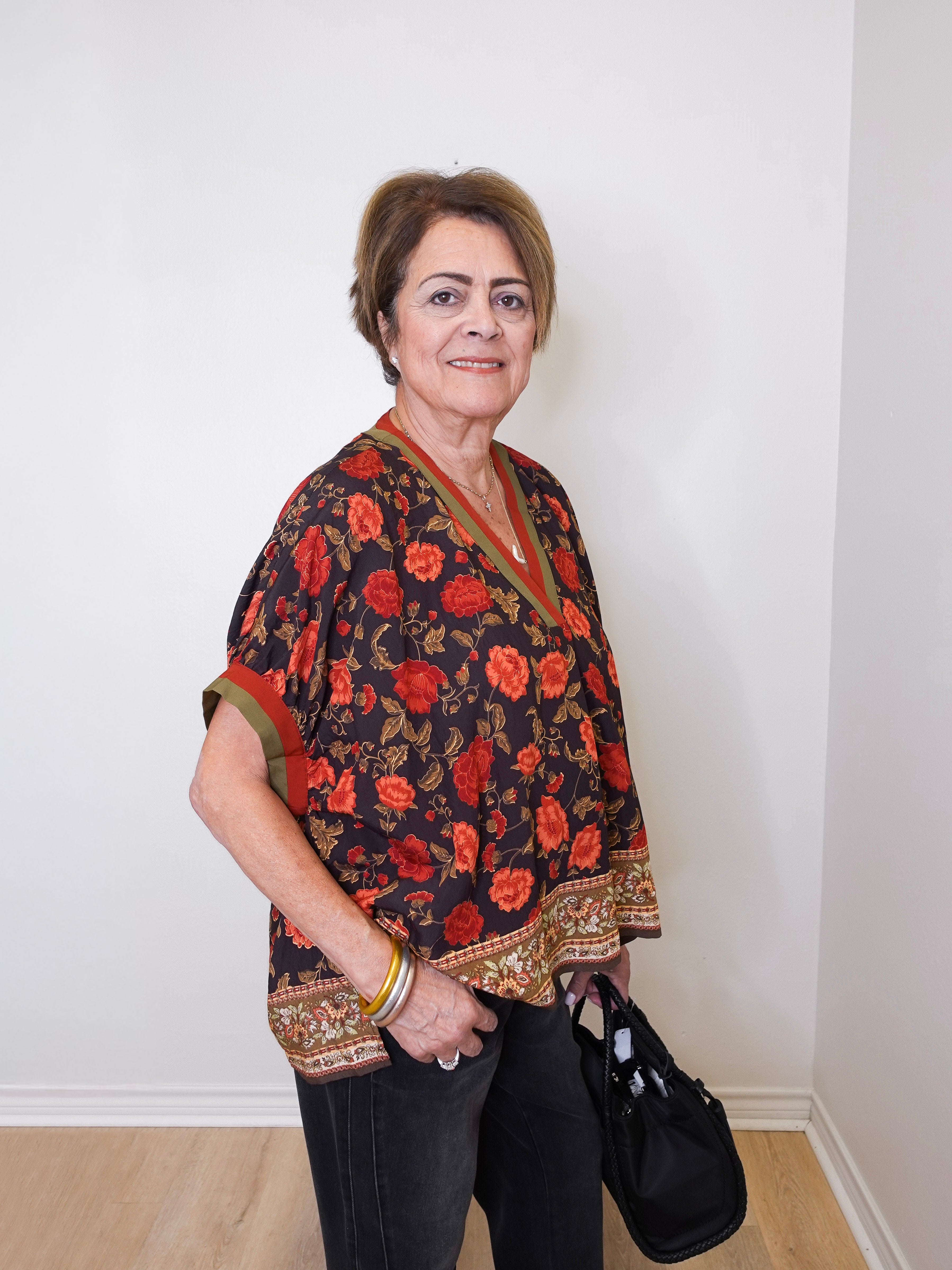 a women wearing a black short sleeve floral print top with black pants, on a white background 