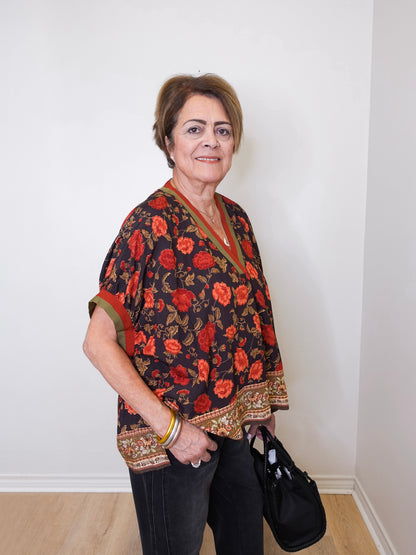 a women wearing a black short sleeve floral print top with black pants, on a white background 