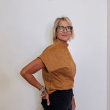 Person wearing a brown turtleneck shirt and black pants against a white background