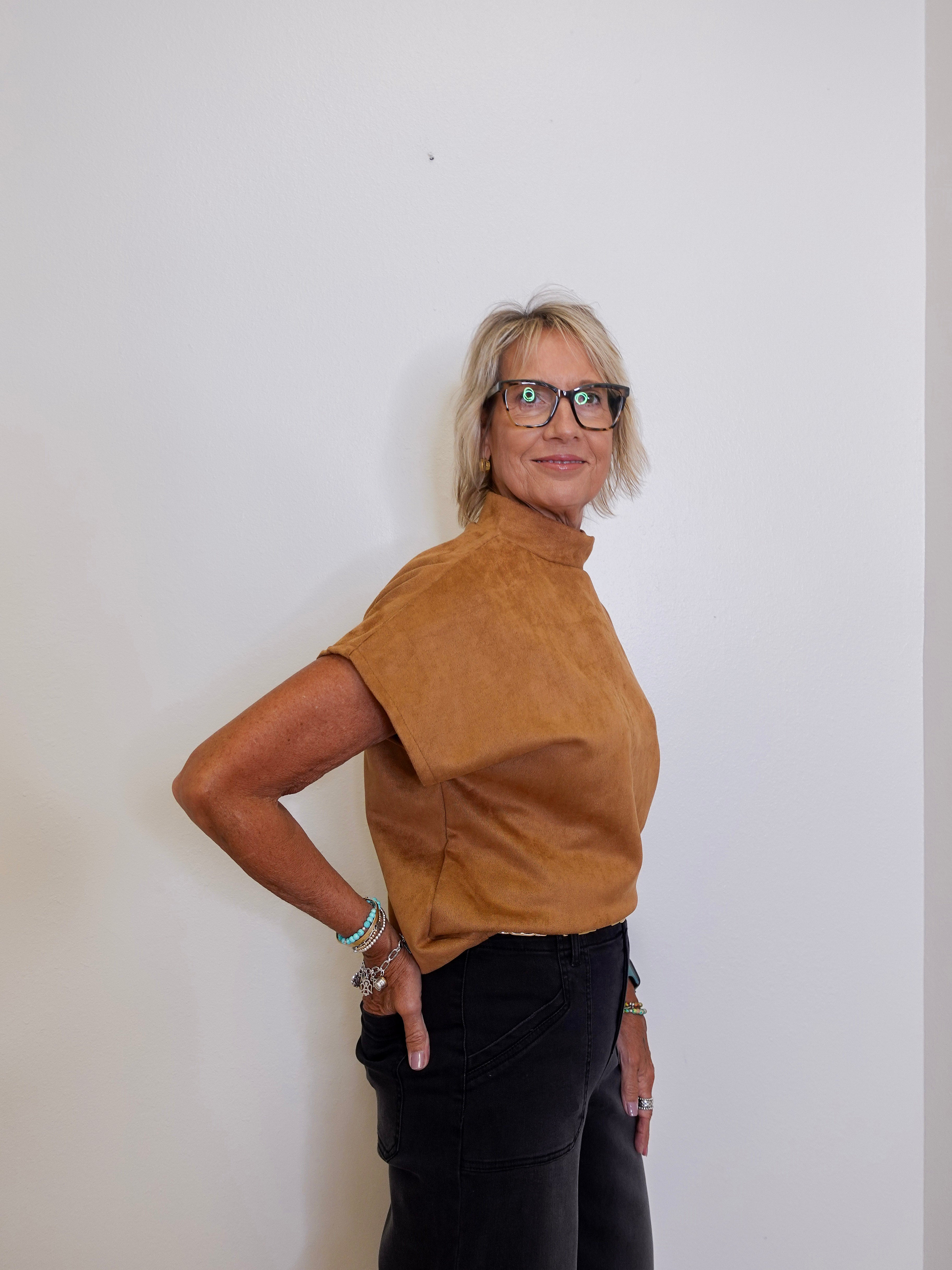 Person wearing a brown turtleneck shirt and black pants against a white background