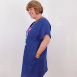 Woman wearing a blue dress with a colorful graphic on a plain background